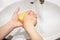 A young girl washes her hands with soap in the bathroom close-up. Hygiene. A teenage girl washes her hands in a white washbasin. W