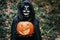 Young girl wearing mysterious Halloween dress holding scary pumpkin - Focus on face