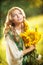 Young girl wearing Romanian traditional blouse holding sunflowers outdoor shot. Portrait of beautiful blonde girl with sunflowers