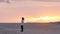 Young girl wearing white anorak and jeans, on the beach watching an autumn sunset