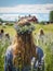 Young girl wearing a wreath of wild flowers on her head, walking in the green meadow with a group of friends. Generative AI