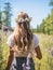 Young girl wearing a wreath of wild flowers on her head, walking in the green meadow in rural landscape. Generative AI