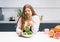 Young girl with weight problems holding fresh salad casting trying to chew it. Curvy body young woman with long blond