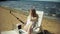 A young girl in a white bikini lies and sunbathes on a deckchair on a sea sandy beach and photographs on a smartphone