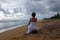 Young girl in a white dress meets the sunset on the beach of the tropical ocean