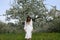 Young girl in white dress near blooming apple tree