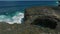 A young girl in a white dress stands on the rocks on the shore of the Indian Ocean. Aerial footage of surge of waves at