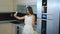 A young girl in a white dress takes a selfie at home in a modern kitchen.