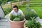 A young girl in a white T-shirt plant a tree in pot at home. Growing seedlings at home.