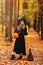 Young girl in witch costume and black long hat holding scary face pumpkin and wooden broom