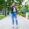 Young girl in a woolen sweater and torn jeans posing in an autumn park