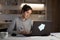 Young girl work on laptop in home evening.Wooden background