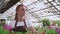 A young girl. worker greenhouse with flowers, takes pictures for site or blog products