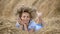 Young girl in a wreath resting in straw haystack