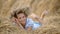 Young girl in a wreath resting in straw haystack