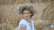 Young girl in a wreath resting in straw haystack