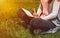 Young girl writes with pen in notebook sitting on green grass in park