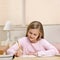 Young girl writing homework in notebook