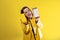 young girl on yellow background uncovering a box