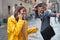 A young girl in a yellow raincoat is having a collision with a passerby while talking on the smartphone on the street on a rainy