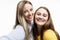 Young girls in bright T-shirts take selfies and laugh. Relations and friendship. White background. Close-up