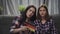 Young girls discussing football match while sitting on sofa in modern apartment.