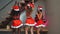 Young girls European, Asian and African in red New Year`s clothes and a hat dance at a Christmas tree and smile