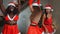 Young girls European, Asian and African in red New Year`s clothes and a hat dance at a Christmas tree and smile