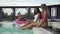 Young girls have fun in the outdoor swimming pool creating huge water splashes by slim slender legs. Leisure and fun of