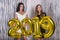 Young girls holding golden 2019 balloons in studio