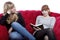 Young girls read a book on red sofa