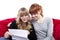 Young girls on red sofa reading a letter