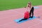 Young girls in the red sweater in nature doing stretching. Coach stretches partner on the twine. Classes in the park. Health.