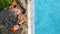 Young girls relax near swimming pool in sunbed deckchairs, women friends have fun on vacation in hotel resort, aerial view