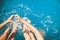 Young girls sit on the edge of swimming pool and chat with their feet in the water and hold their hands in heart