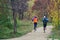 Young girls are training on the run in the autumn park alley. Activity and sport. Unrecognizable