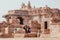 Young girls watching pictures in phone past walls of the 7th century Hindu temples, India