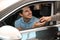 Young  giving car key to customer in modern auto dealership, closeup