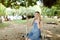 Young gladden woman riding swing and speaking by smatrphone, sand and tree in background.