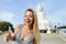 Young gladden woman showing thumbs up, white Buddha statue in Phuket in background.