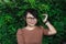 Young glasses Asian woman in brown shirt smiling touching green leaves