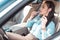 Young good-looking woman in formal clothes, applying lipstick in car, using a sun