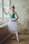 Young and graceful ballerina in pointe shoes and a tutu dances in the studio. Choreography and dancing classes concept.