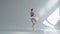 Young graceful ballerina in pointe shoes and white ballet tutu makes pirouette. Shot on a white background in the