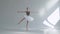 Young graceful ballerina in pointe shoes and white ballet tutu makes pirouette. Shot on a white background in the