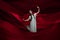 Young and graceful ballet dancer on billowing red cloth background in classic action. Art, motion, action, flexibility