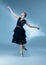 Young and graceful ballet dancer in black stage outfit, dress  on white blue studio background in neon light.