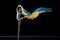Young graceful classic ballerina dancing with cloth painted in blue and yellow colors of Ukraine flag on dark studio