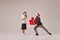 Young and graceful couple of ballet dancers in warm winter clothes dancing with festive gift boxes on grey background