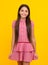 Young graceful teenager child in dress isolated on yellow background. Beautiful teen in summer clothing.
